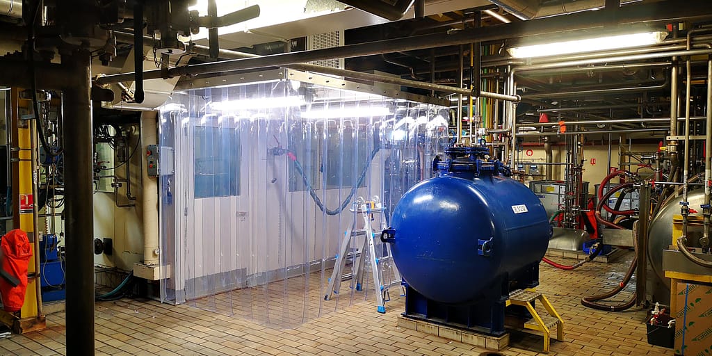 Zone d’air propre localisée en atelier industriel avec rideaux antistatiques et plafond soufflant
